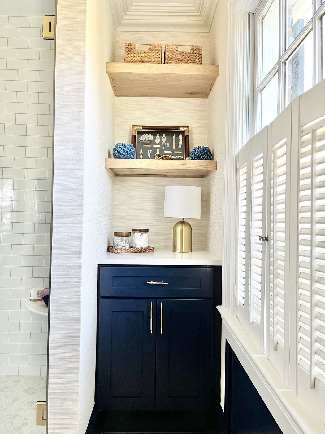 Bath nook with navy cabinet, open oak shelves, and plantation shutters