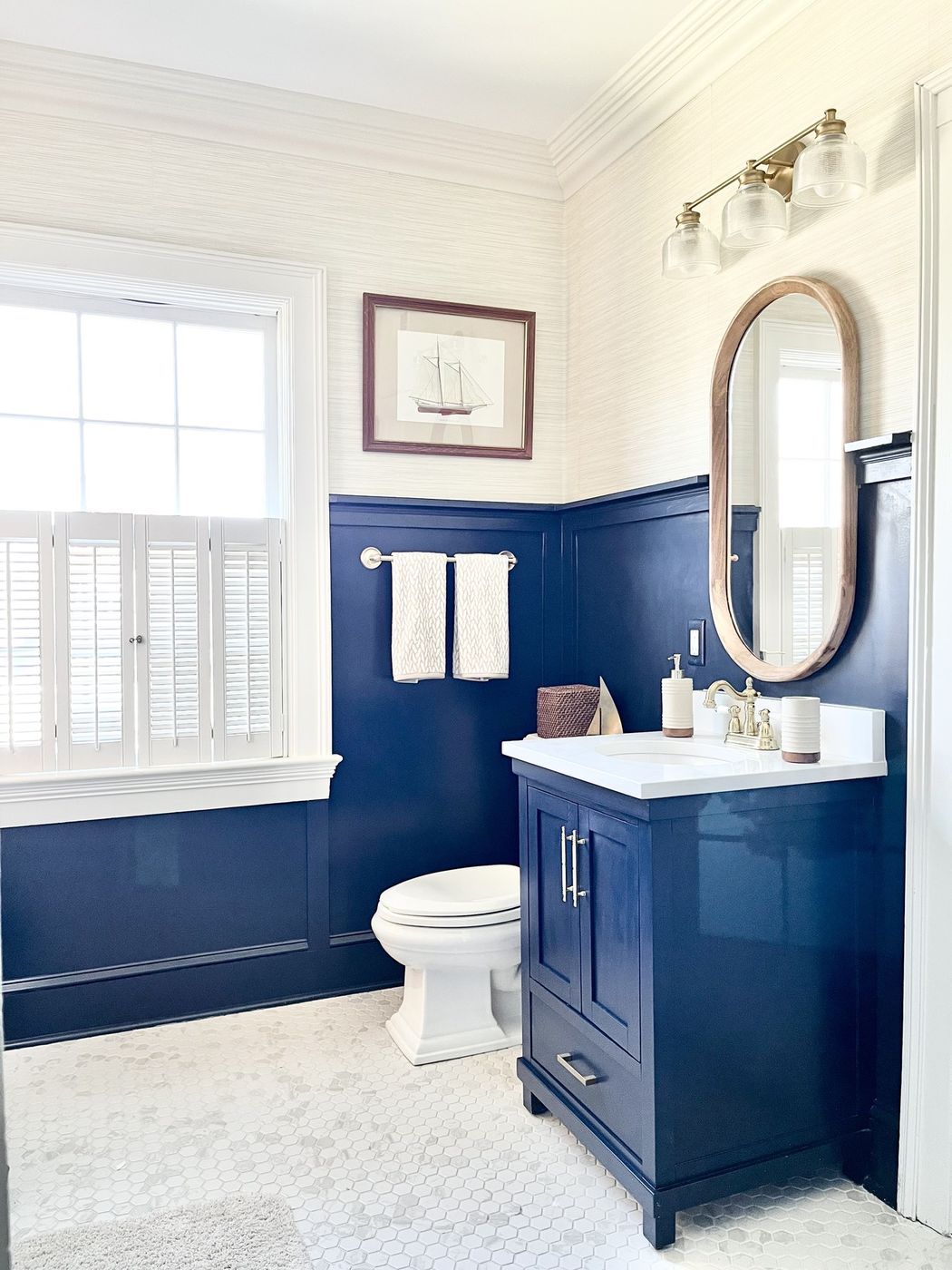Bathroom with navy wainscoting, a navy vanity, and brass fixtures