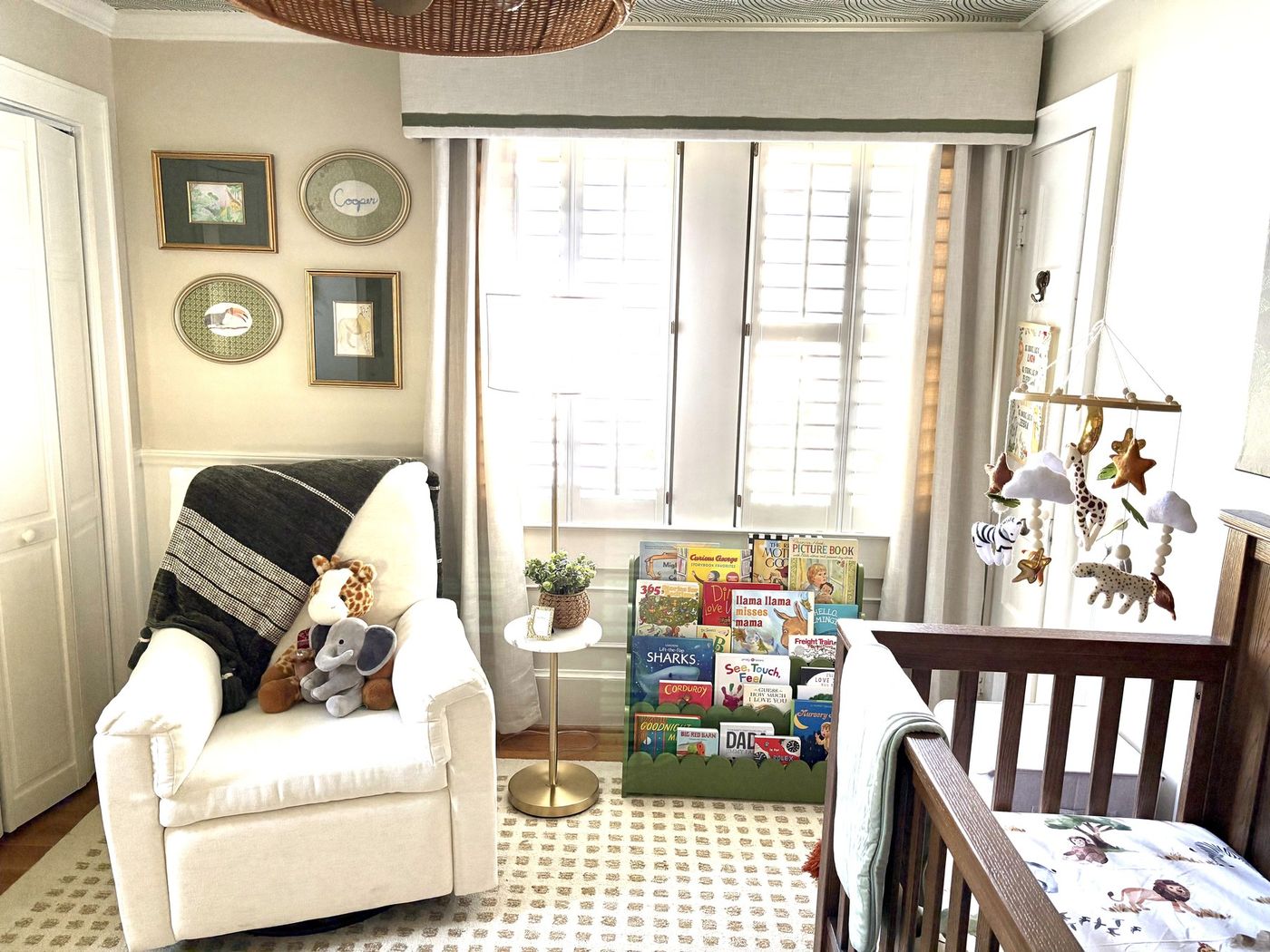 Nursery reading corner with a white glider, book ledge, and shuttered windows