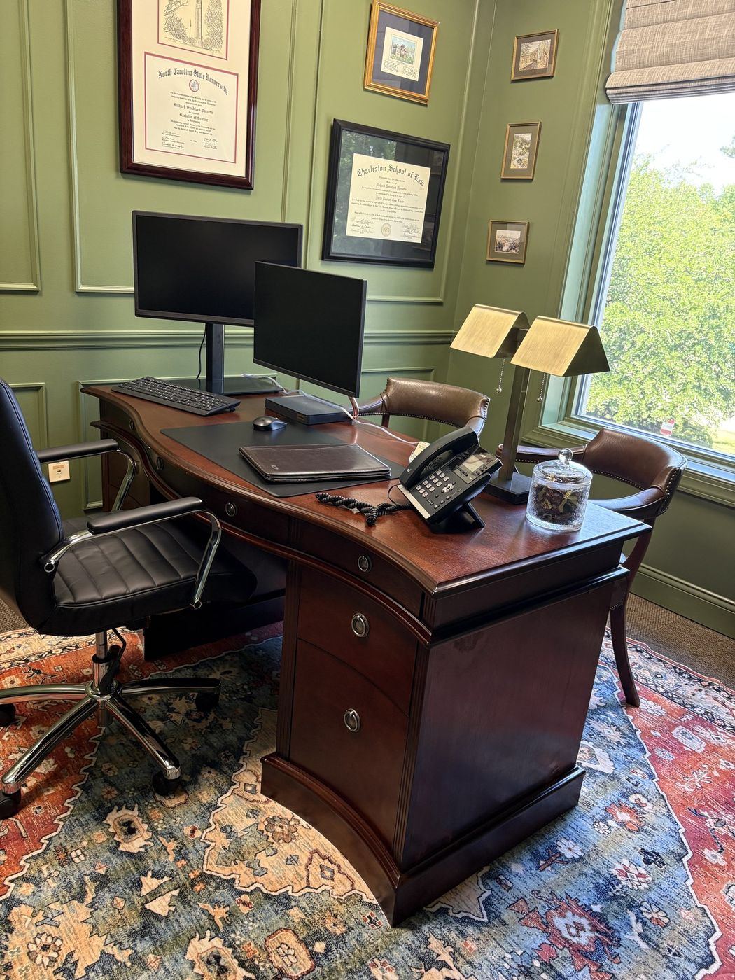 Office with sage green paneling, a cherry desk, and a vintage rug
