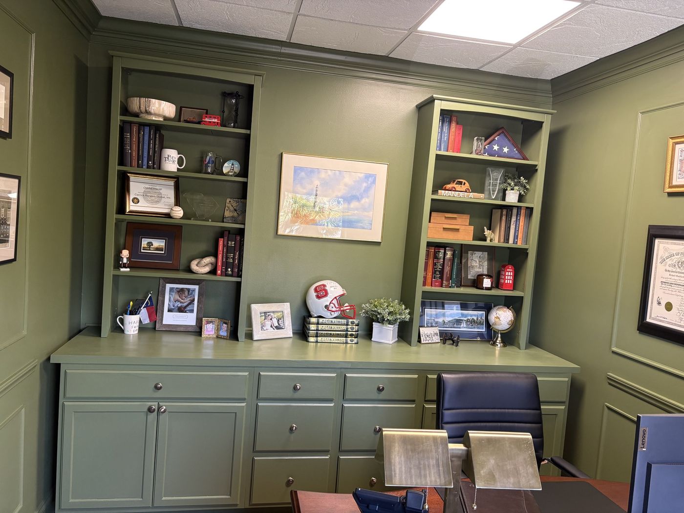 Sage green built-in bookcases and cabinets in an office